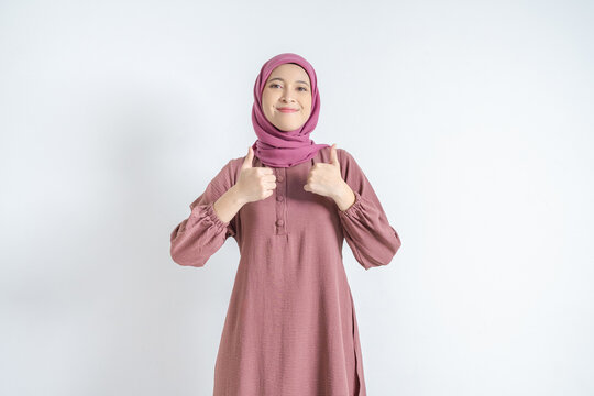 Happy Asian Muslim woman in hijab showing double thumbs up gesture on white background