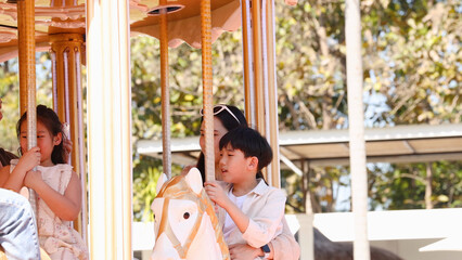 Young Asian Boy and Family Riding a Carousel at an Amusement Park © blueringmedia