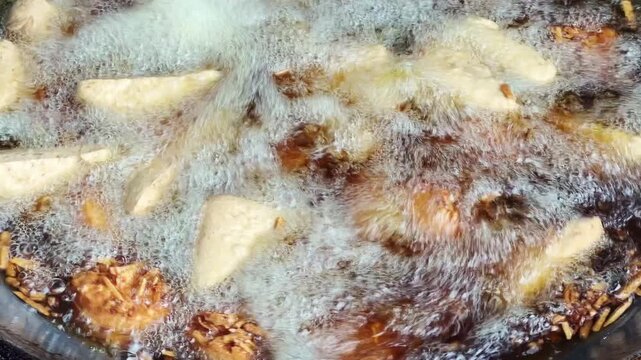 Close up shot of deep frying tofu and taro in hot boiling oil in big wok street food.
