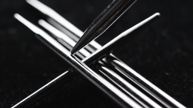 Shiny metal double-pointed knitting needles creating an abstract pattern