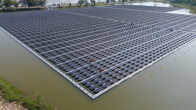 An aerial view shows workers cleaning solar panels in a large body of water.