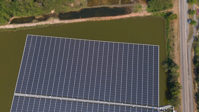 An aerial view shows workers cleaning solar panels in a large body of water.