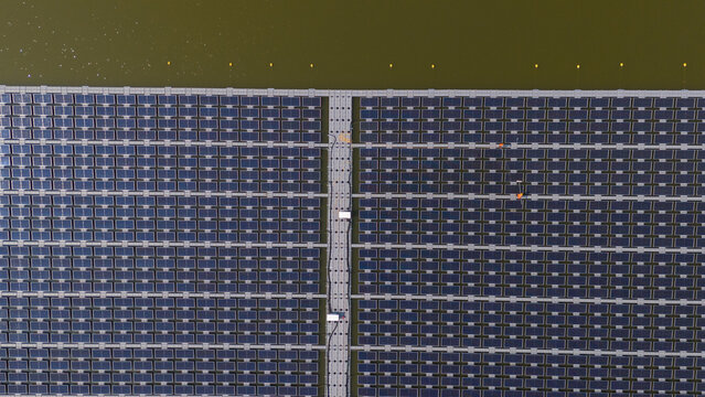 An aerial view shows workers cleaning solar panels in a large body of water.