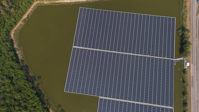 An aerial view shows workers cleaning solar panels in a large body of water.