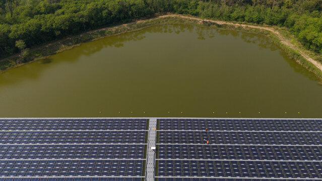 An aerial view shows workers cleaning solar panels in a large body of water.