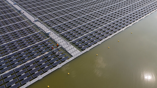 An aerial view shows workers cleaning solar panels in a large body of water.