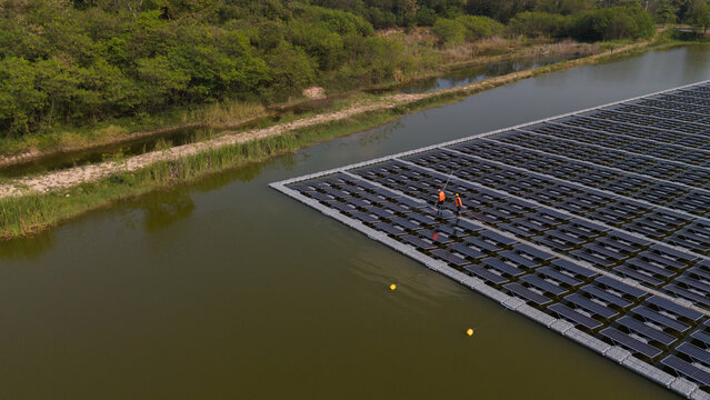 An aerial view shows workers cleaning solar panels in a large body of water.