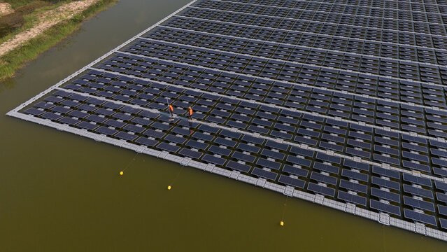 An aerial view shows workers cleaning solar panels in a large body of water.