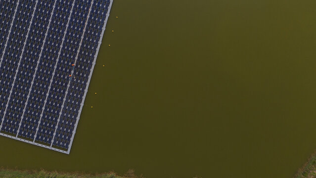 An aerial view shows workers cleaning solar panels in a large body of water.