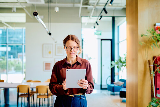 Woman reading and working on a tablet, connecting with technology in a contemporary business environment