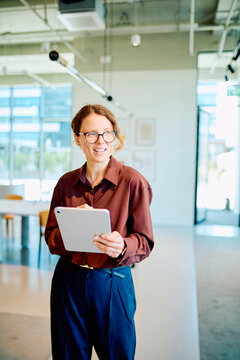 Experienced businesswoman communicating ideas while using a digital tablet, representing technology, leadership, and success in a modern workplace