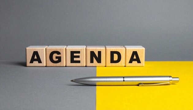 Wooden blocks spelling agenda with pen across color divide