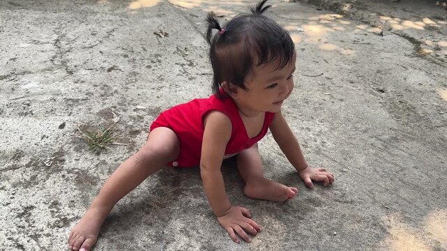Adorable Smiling Baby Girl in Red Romper Sitting Outdoors