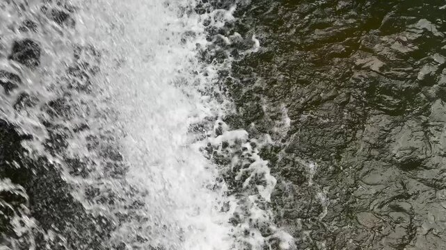 Heavy waterfall striking the ground and creating splashes on a water surface
