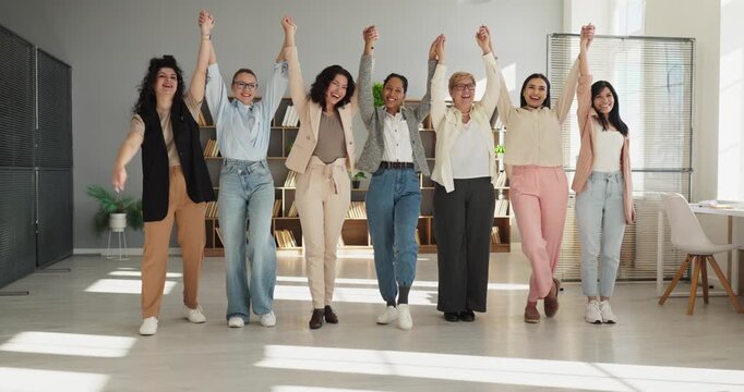 Women business team celebrate unity and success. A group showing diversity raises hands in an office, showing support, achievement and drive for shared goals. Symbol of teamwork and inclusion.