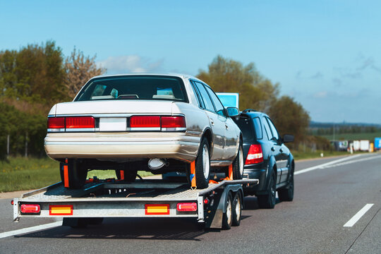 Flatbed tow truck transporting car in nature