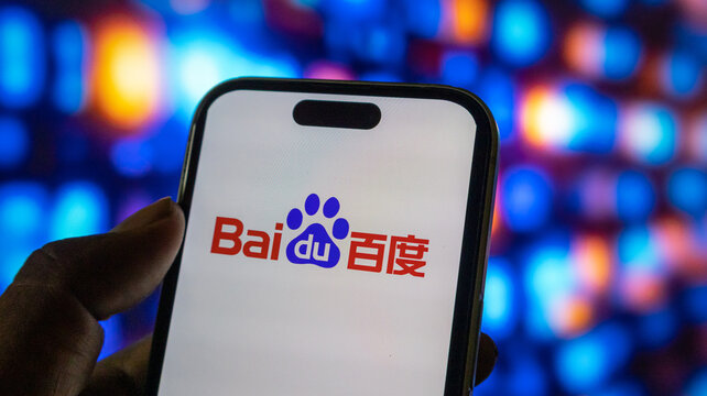 person holding smartphone showing baidu logo against blurred background with blue orange lights.
