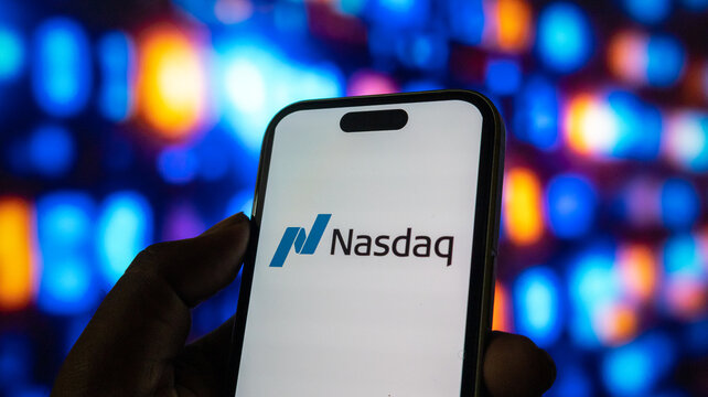 Nasdaq stock exchange logo on smartphone screen held in hand with vibrant bokeh light backdrop.