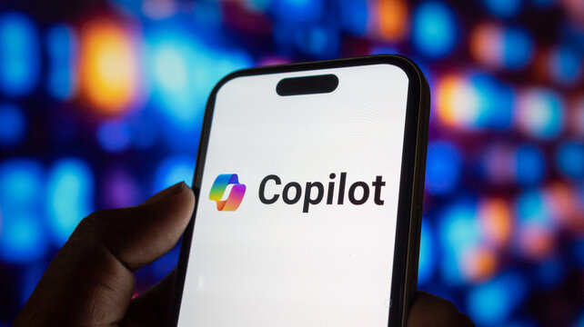 Smartphone screen shows Copilot logo with colorful abstract pattern against bokeh background innovation.
