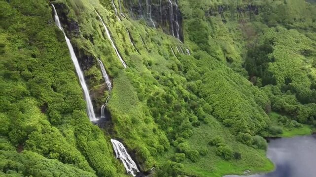 Multiple waterfalls cascading down lush green cliffside at Po&ccedil;o da Ribeira do Ferreiro in Flores Island Azores Portugal