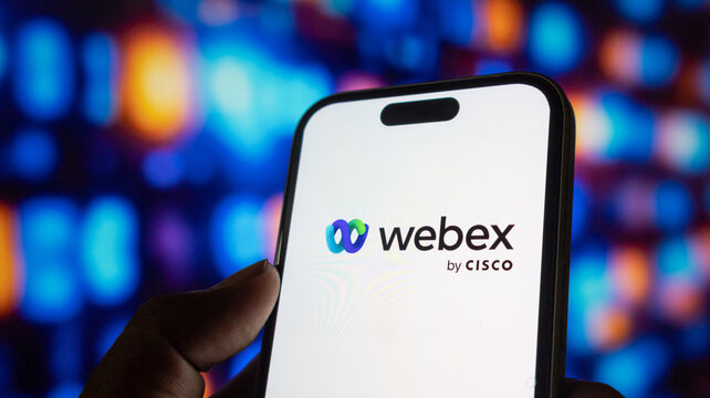 Smartphone displaying cisco webex logo against colorful blurry background with hand holding device.