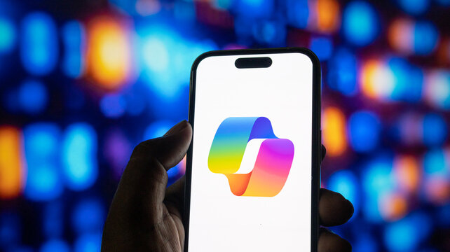 Microsoft copilot ai software logo displayed on smartphone screen held by hand in dark interior.