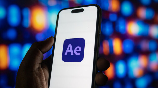Close up of person hand holding smartphone with adobe after effects app icon on screen display.
