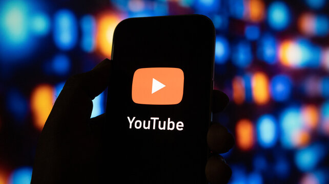 Smartphone displaying youtube logo against colorful blurred bokeh lights background digital media.
