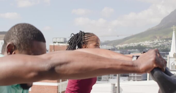 African woman and man exercising smiling leaning grasping handles on roof maroon top