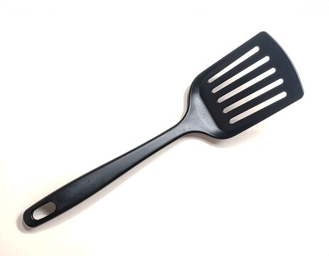 Black plastic kitchen spatula with a slotted head isolated on a white background