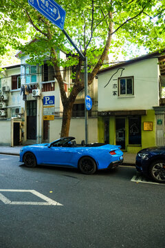 Shanghai, China, Asia - July 11, 2027: A blue Ford Mustang convertible is driving on a street in downtown Shanghai.