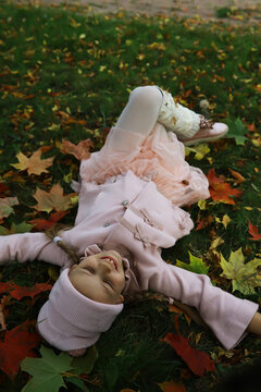 Joyful Child in Pink Coat Lying on Colorful Autumn Leaves in a Park