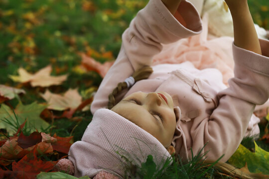 Girl Relaxing on Autumn Leaves in Cozy Pink Outfit