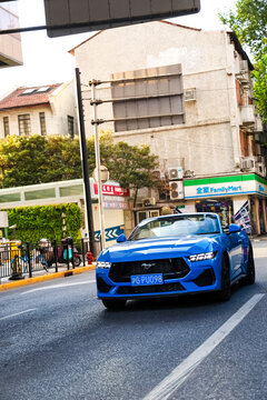 Shanghai, China, Asia - July 11, 2027: A blue Ford Mustang convertible is driving on a street in downtown Shanghai.