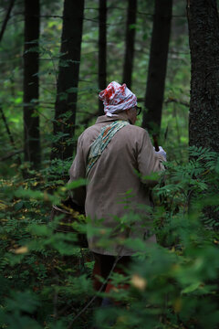 Elderly Woman Foraging in Dense Forest with Basket on Misty Day