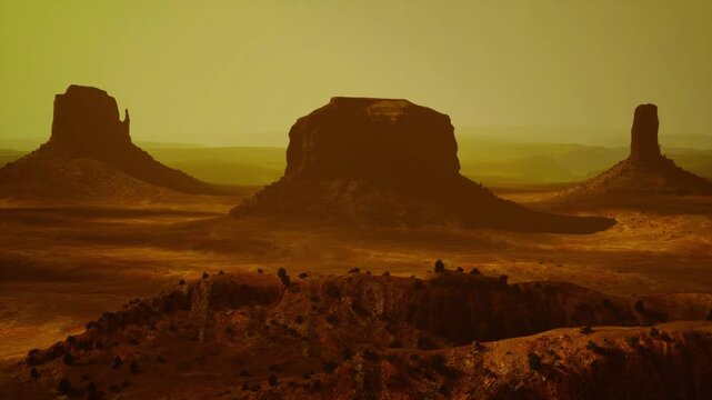 Golden buttes framed by rocky ridge at sunset, warm backlight and long silhouettes, amber haze and dramatic western mood with textured sandstone foreground.