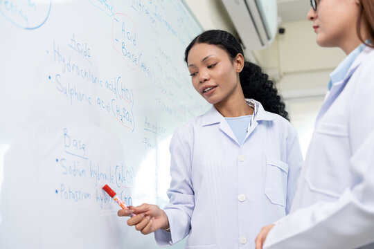 African American scientist writing on whiteboard in laboratory