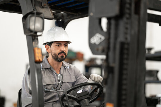 Forklift operator driving in industrial warehouse or factory