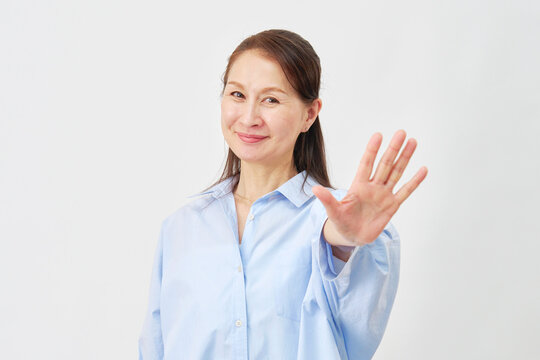 白背景で制止する高齢女性