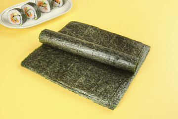 Dried Nori Seaweed Sheets with Vegetable Sushi on Yellow Background © LyVan