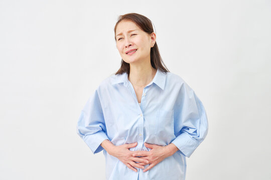 白背景で腹痛に悩む女性