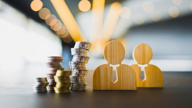 Wooden human figures with money coins stack. Human resources management, team investment, payroll budget, financial planning concept.