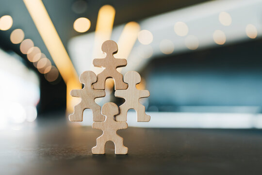 Wooden people figures forming pyramid structure. Business teamwork, organizational hierarchy, unity, leadership, partnership concept.