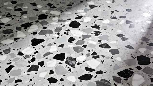 terrazzo flooring style, characterized by a speckled pattern. The layout consists of irregularly shaped chips in black, gray, and white, embedded in a light gray cementitious base. The chips vary in s