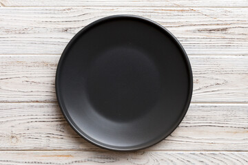 Naklejka premium Top view of black plate on wooden background. Empty space for your design