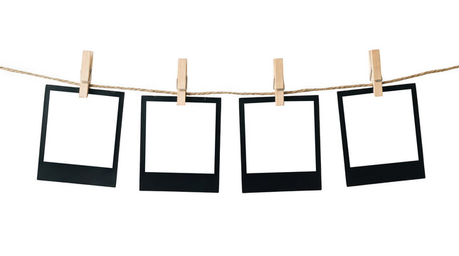 Four blank black instant photo frames hanging on a rope isolated on transparent background