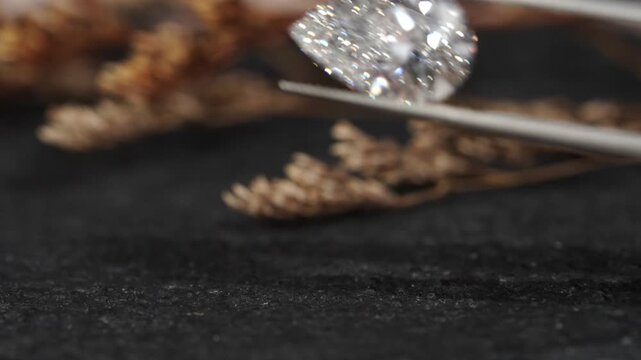 Exquisite pear-shaped diamond with swaying slightly with sparkles brilliantly in tweezers, showcasing rare luxury and investment value