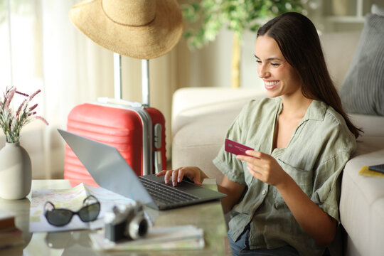 Happy tourist booking online with a laptop and credit card