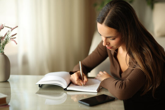 Woman taking notes in paper agenda handwriting in a house