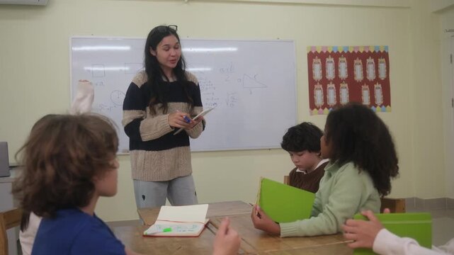 The teacher is teaching young children in a class at school.